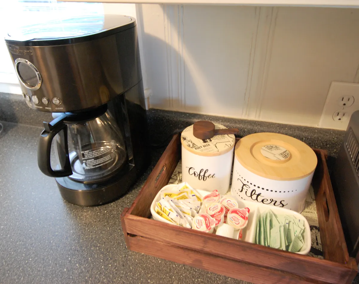 A close-up of a coffee maker setup with a wooden tray and containers, evoking the comfort of enjoying a morning beverage before heading out for a day of exploration.